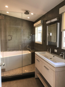 We are seeing a lot of trendier bathrooms employ concrete-look tiles in decorative panels, walls, floors, etc. This a part of what gave this bathroom reno its vogue feel.